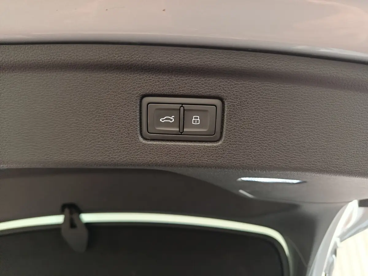 Boutons d'ouverture et de verrouillage du coffre sur la garniture intérieure du hayon d'un Audi A5 gris clair.