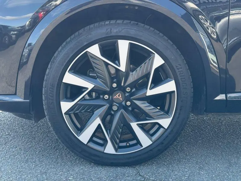Gros plan sur la roue avant gauche du CUPRA Formentor 1.5 eTSI Hybrid noir Minuit, mettant en valeur la jante au design géométrique bicolore.