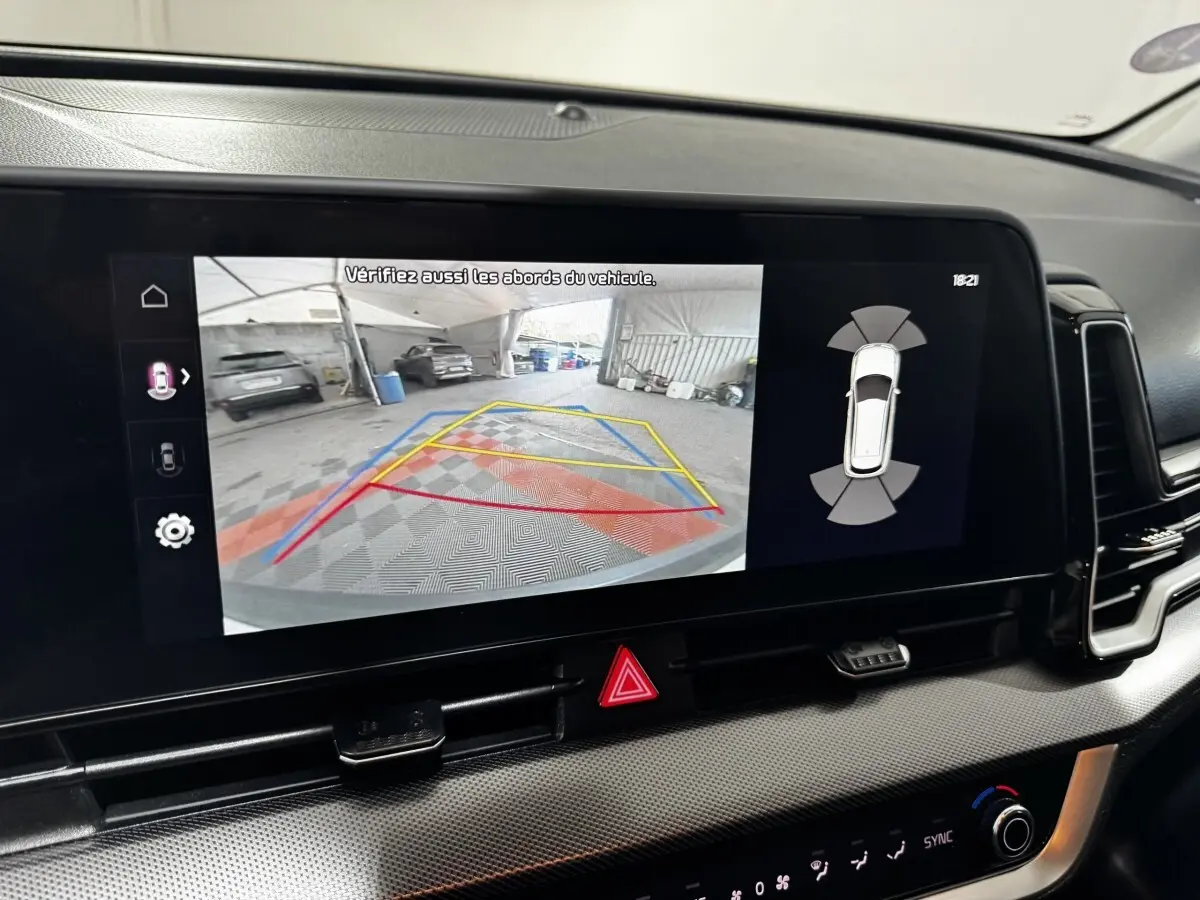 Écran tactile intérieur montrant la caméra de recul et l'aide au stationnement du Kia Sportage blanc 2024.