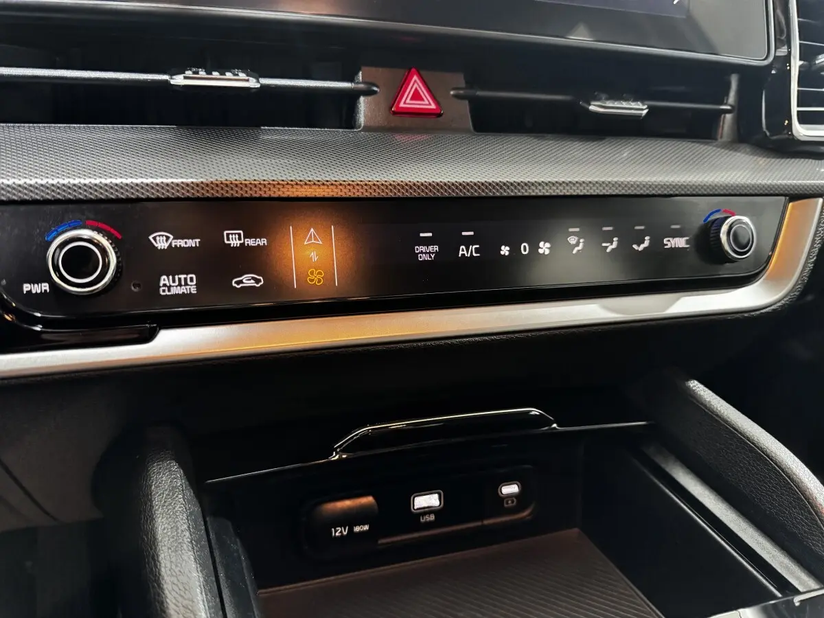 Détail du tableau de bord noir du Kia Sportage 2024 avec commandes climatisation digitales et ports USB et 12V.