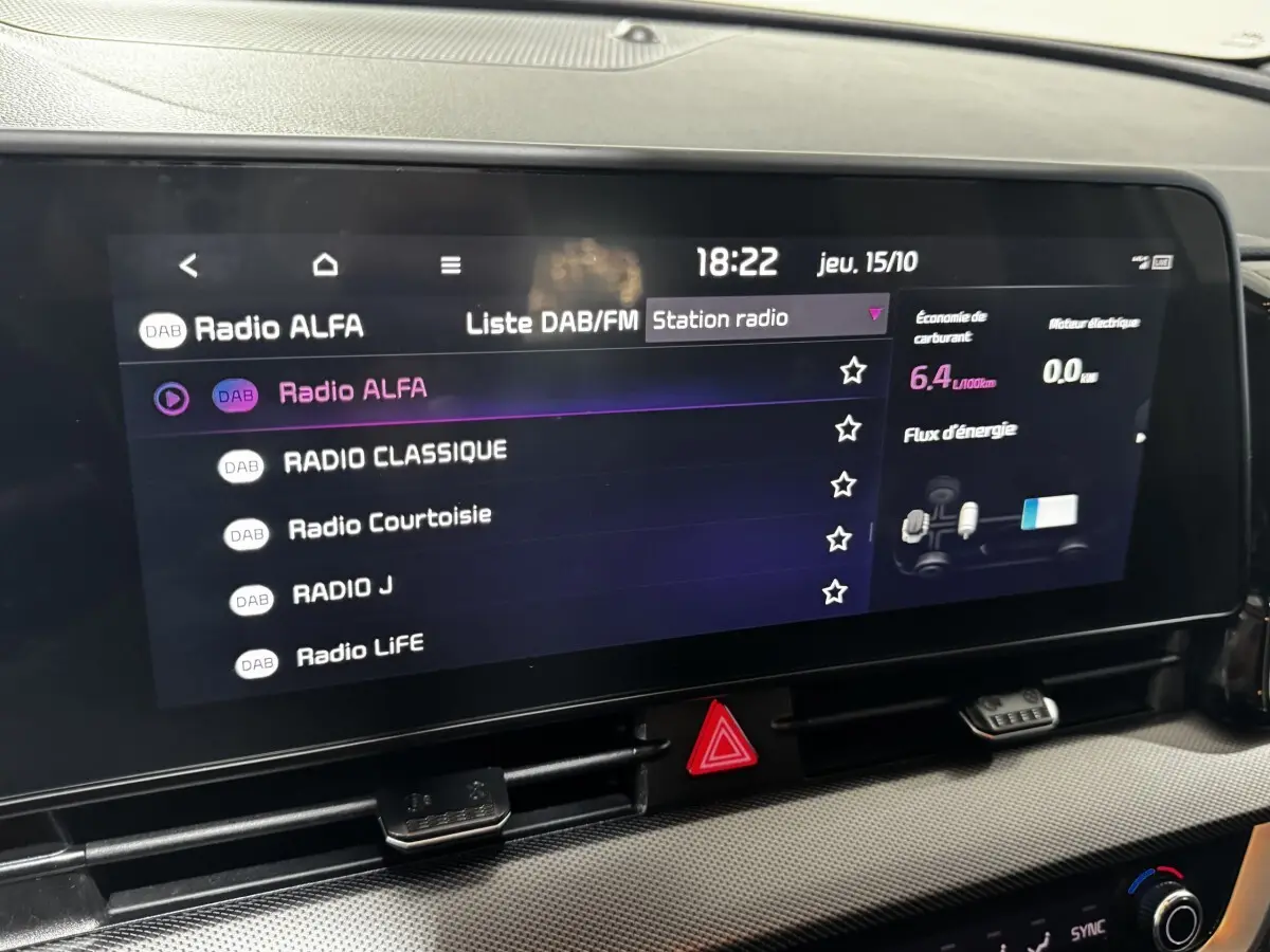 Écran tactile central du tableau de bord du Kia Sportage blanc 2024 affichant les stations radio DAB/FM.