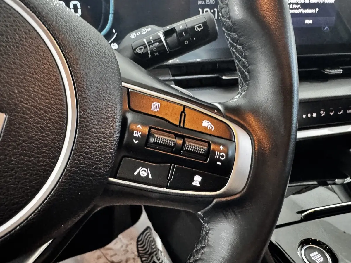 Gros plan sur le volant cuir noir de la KIA SPORTAGE 2024 avec commandes multifonctions et tableau de bord digital.