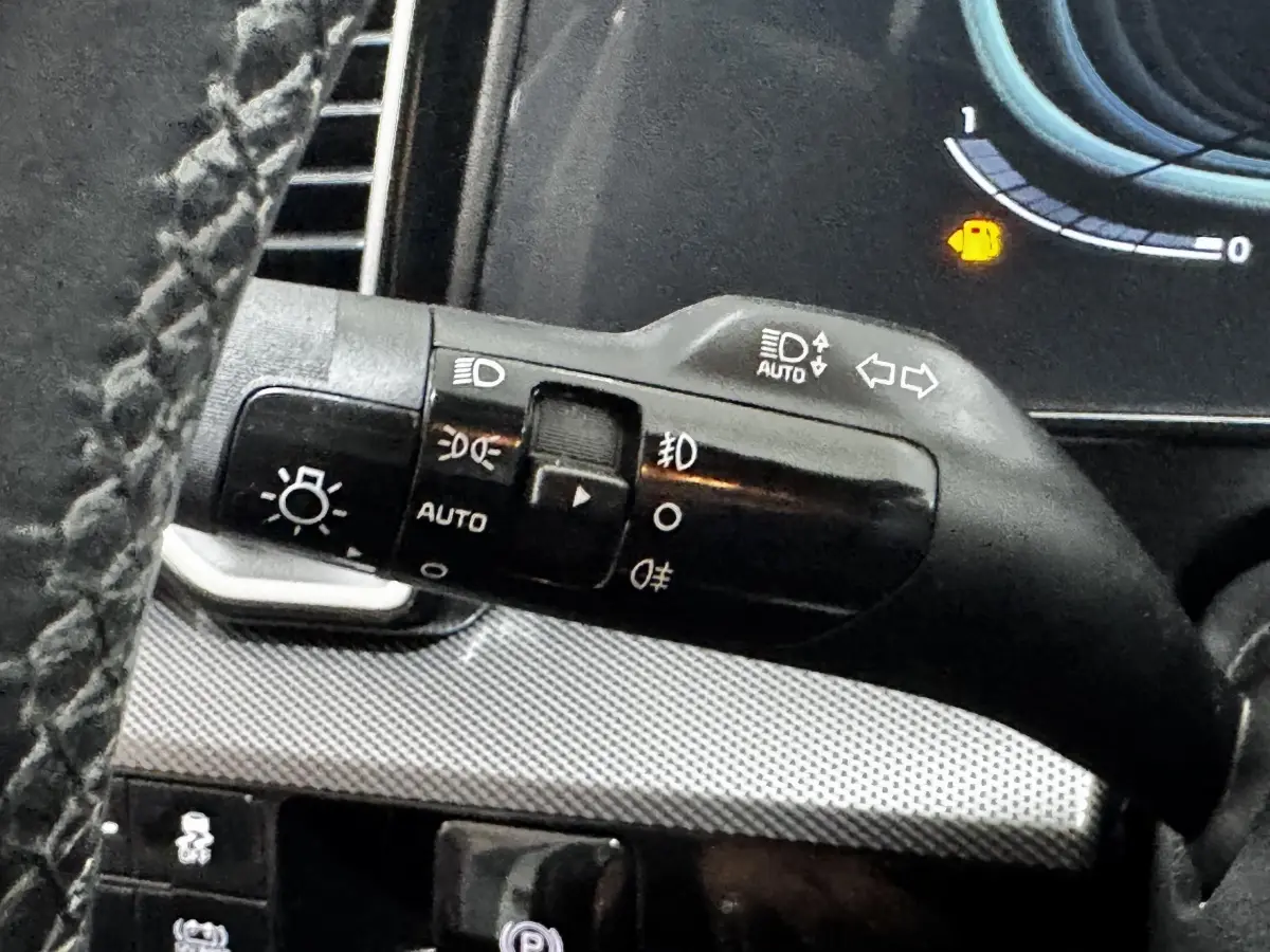 Gros plan sur la commande des phares et clignotants à gauche du volant dans un Kia Sportage 2024.