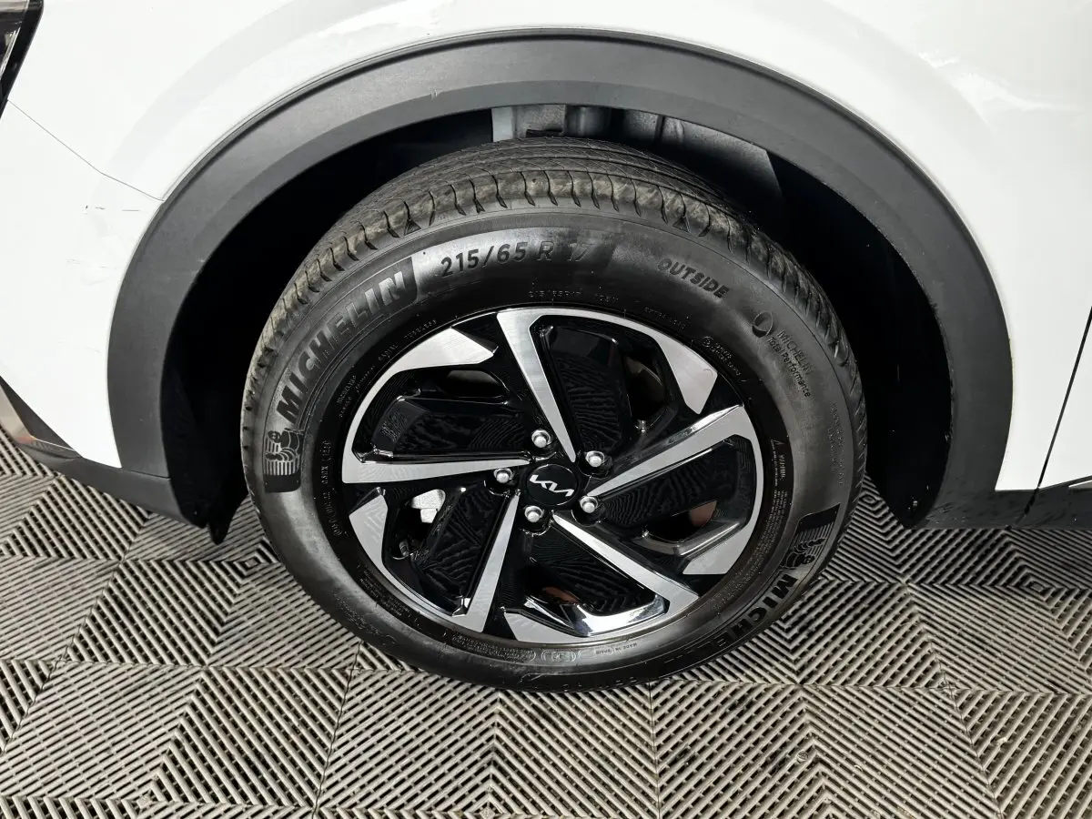 Gros plan sur la roue avant droite du KIA SPORTAGE blanc 2024 avec jante alliage noire et argentée Michelin.