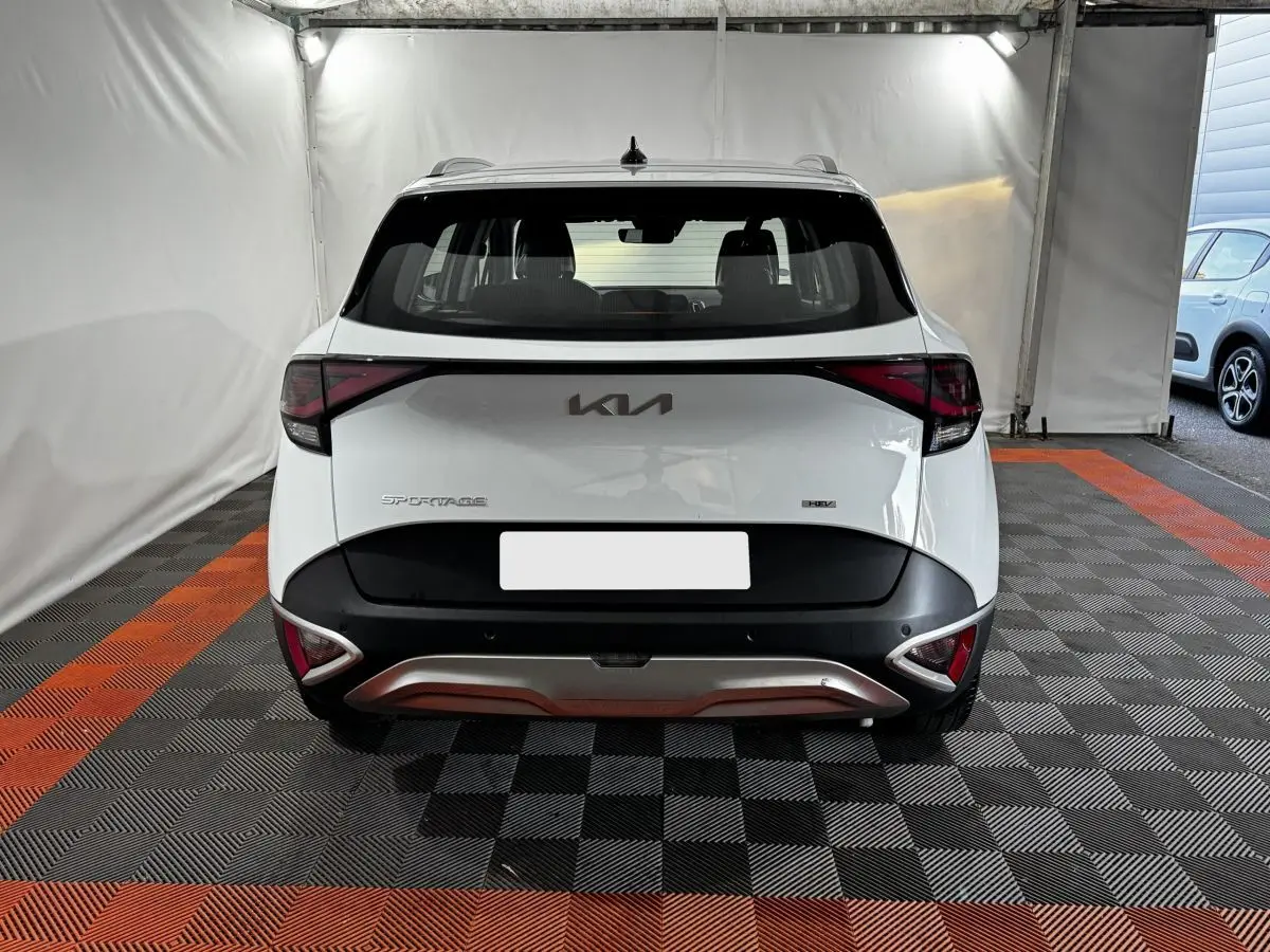 Vue arrière d'un KIA Sportage blanc 2024 avec feux arrière en forme de flèche et logo KIA central.