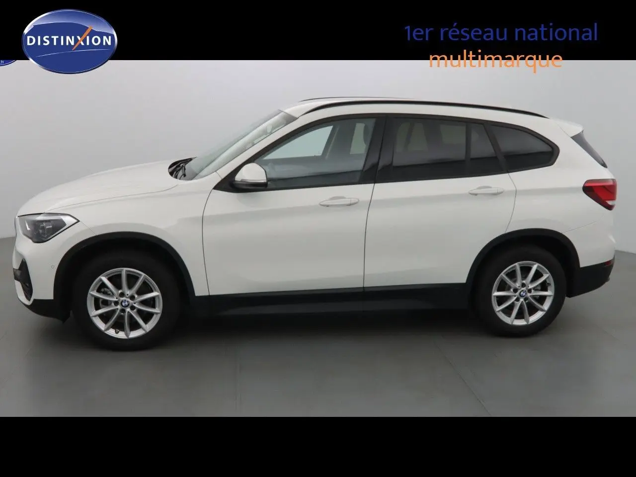 Profil côté gauche d'un BMW X1 blanc Alpine Metal 2022 avec jantes alliage et vitres teintées.