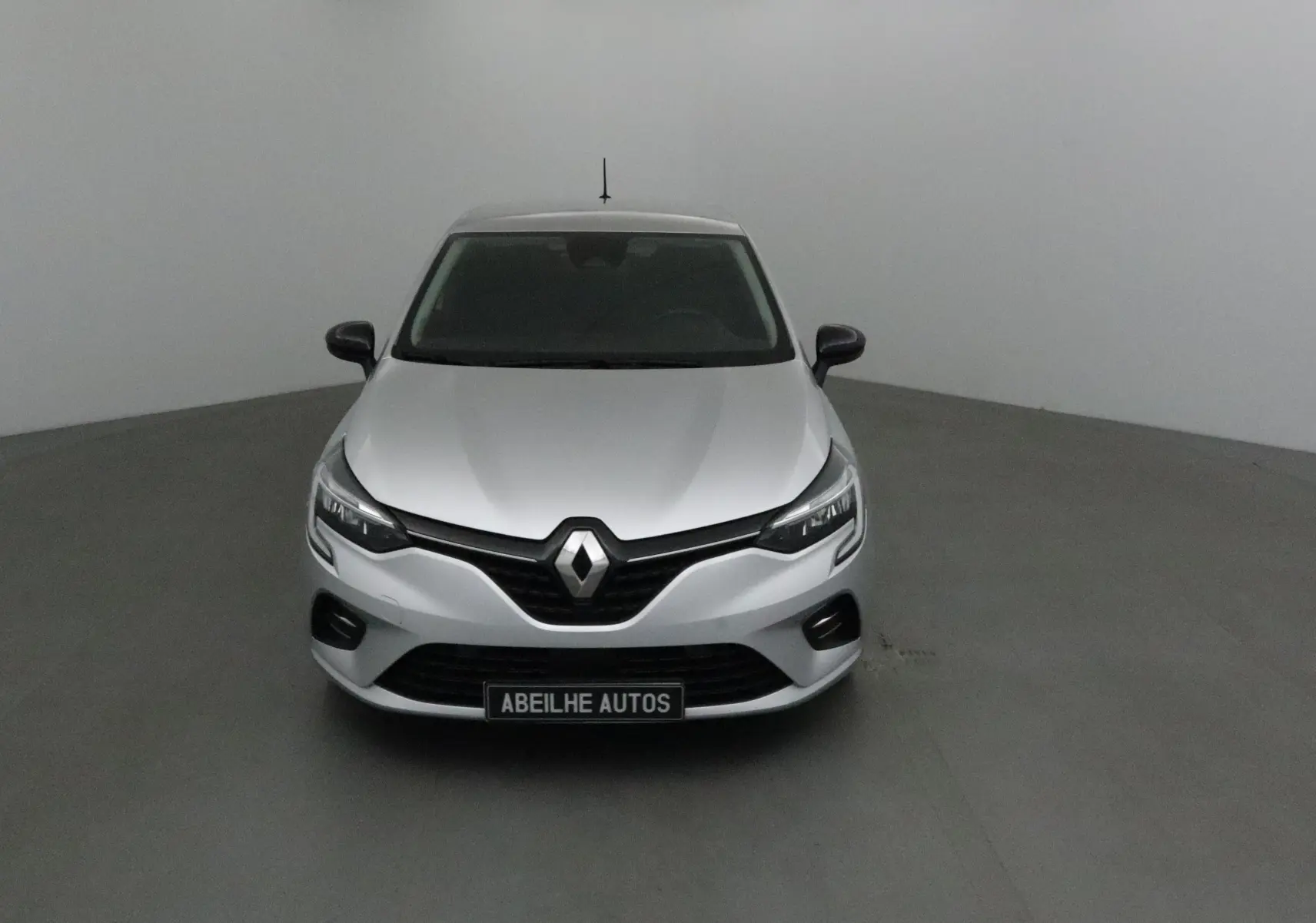 Vue frontale d'une Renault Clio V gris platine avec calandre noire et phares LED, sur fond neutre en studio.