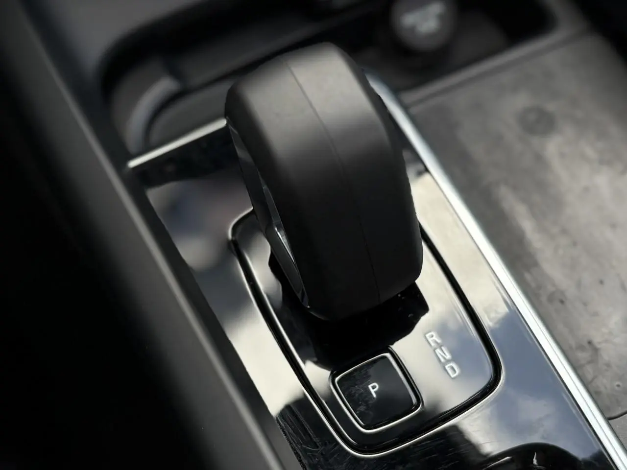 Gros plan sur le levier de vitesse automatique noir dans la console centrale brillante du Volvo XC60 gris silver.