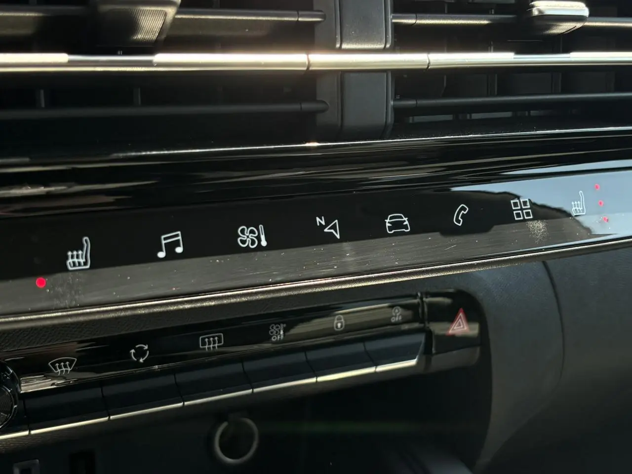 Gros plan sur la console centrale noire brillante du Citroën C5 Aircross Hybrid 2025 avec commandes tactiles et voyants rouges allumés.