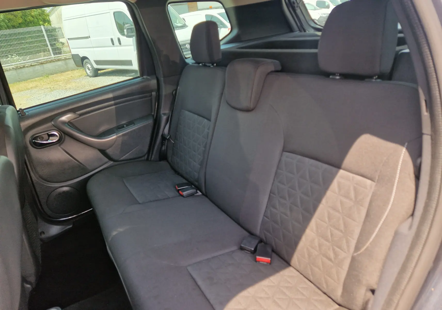Vue intérieure de la banquette arrière du Dacia Duster gris foncé, montrant les sièges tissu avec motifs géométriques.