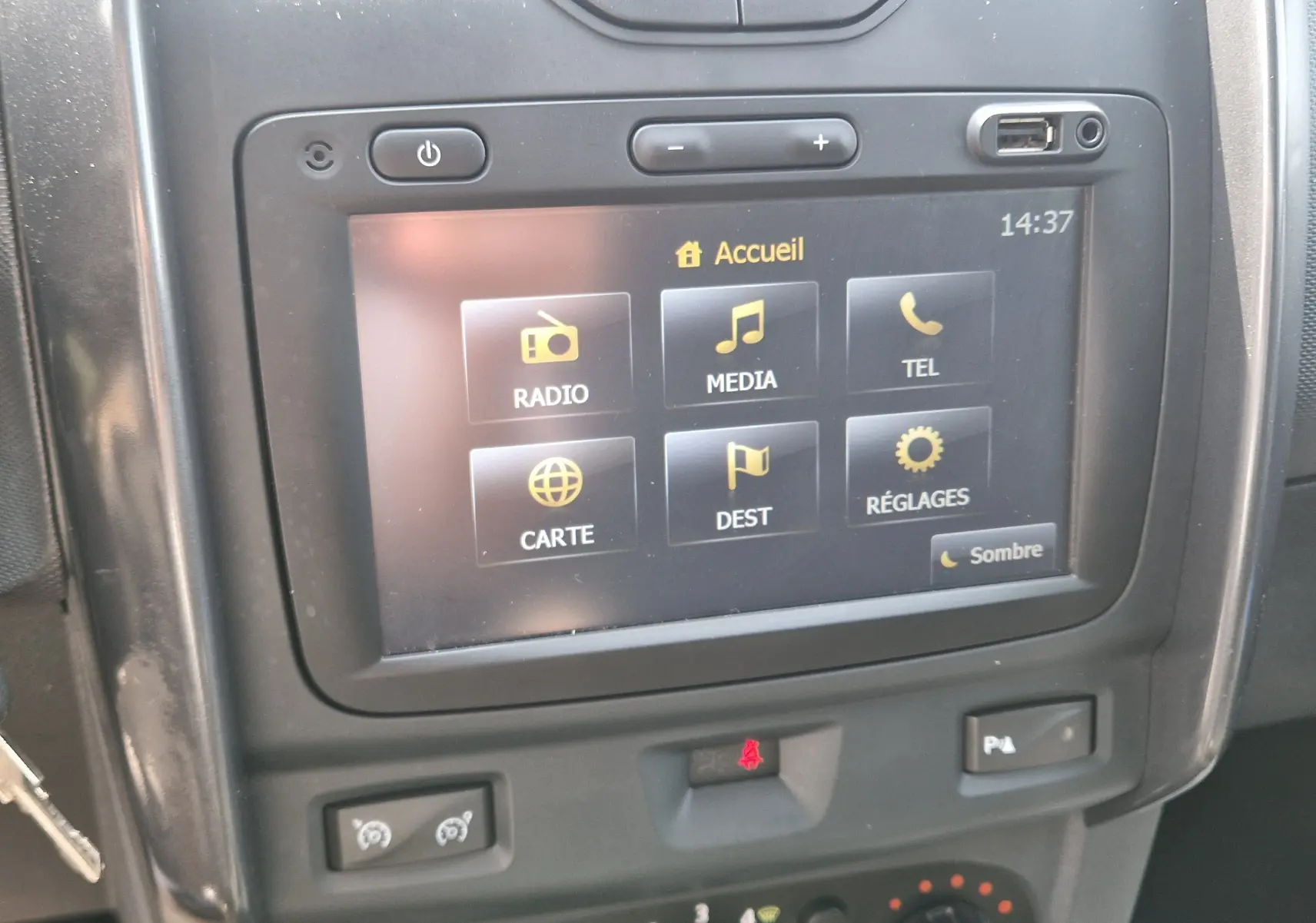 Vue rapprochée de l’écran tactile central du Dacia Duster 2015 gris foncé, affichant le menu principal avec options multimédia.