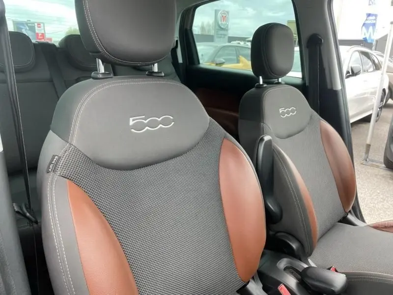Gros plan sur les sièges avant gris et marron de la FIAT 500L beige, avec logo 500 brodé sur les appuie-têtes.