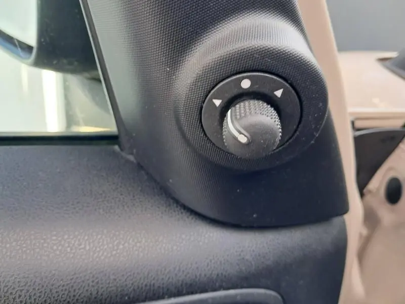 Gros plan sur le bouton de réglage des rétroviseurs côté conducteur d'une FIAT 500L beige de 2014.