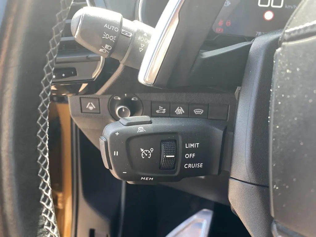 Gros plan sur la commande de régulateur de vitesse à gauche du volant d’un DS7 Crossback jaune clair 2018.