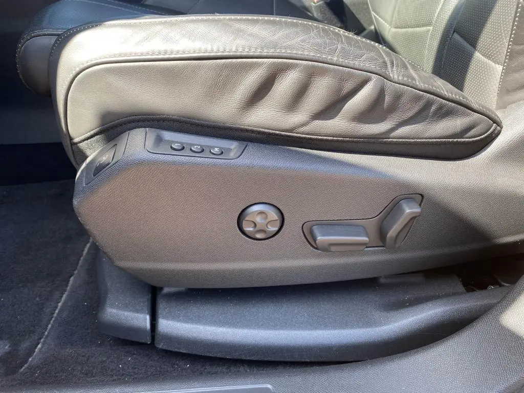 Gros plan sur les commandes de réglage électrique du siège avant en cuir noir du DS7 Crossback jaune clair.