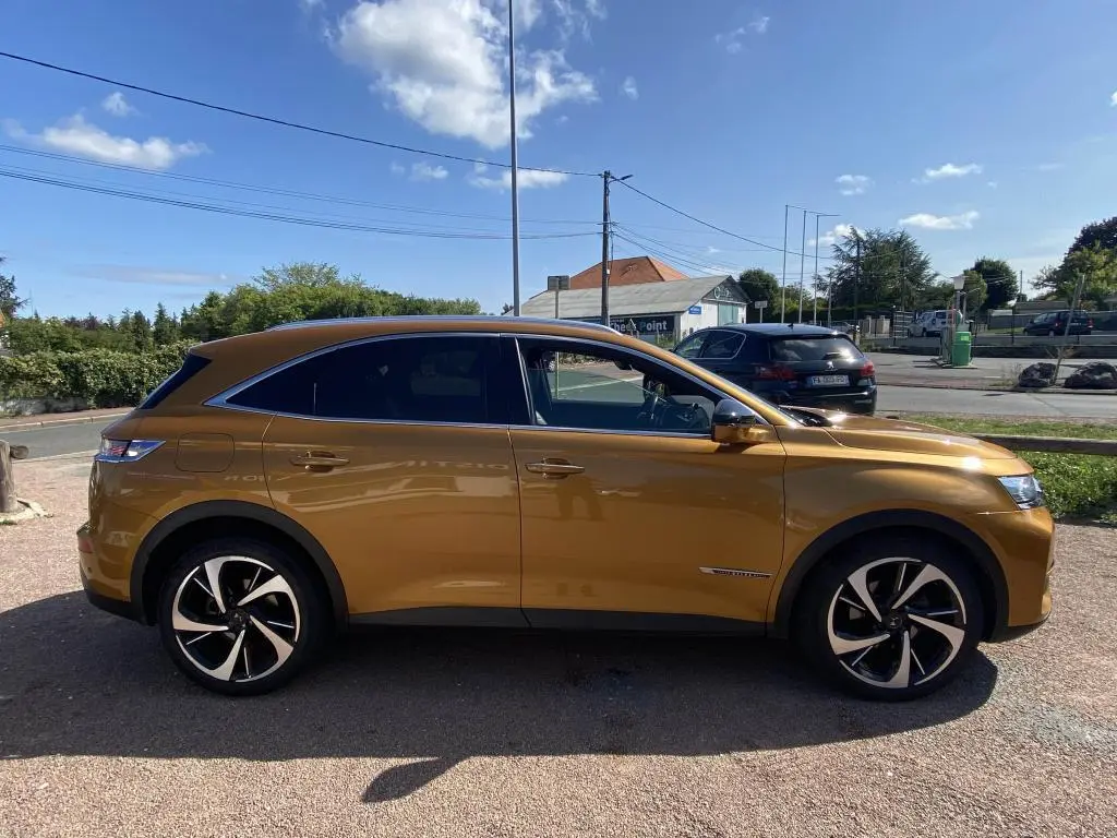 Vue latérale droite d'un DS7 Crossback jaune clair avec jantes noires et chromées, stationné en extérieur.