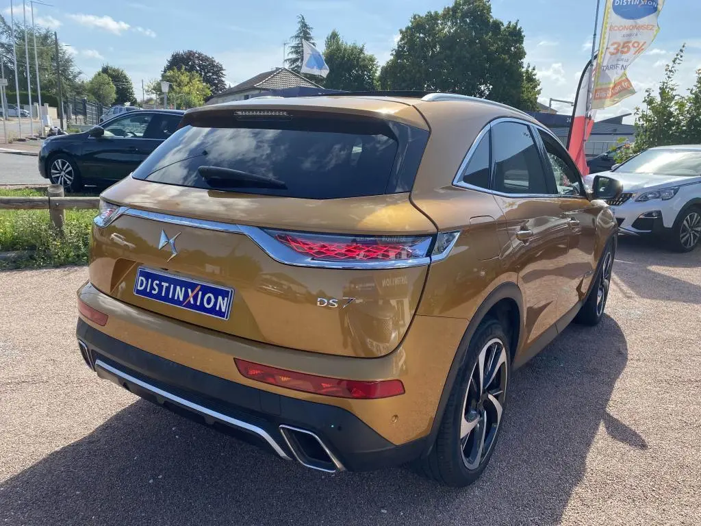 Vue 3/4 arrière droite d'un DS7 Crossback jaune clair avec feux arrière LED et double sortie d'échappement chromée.