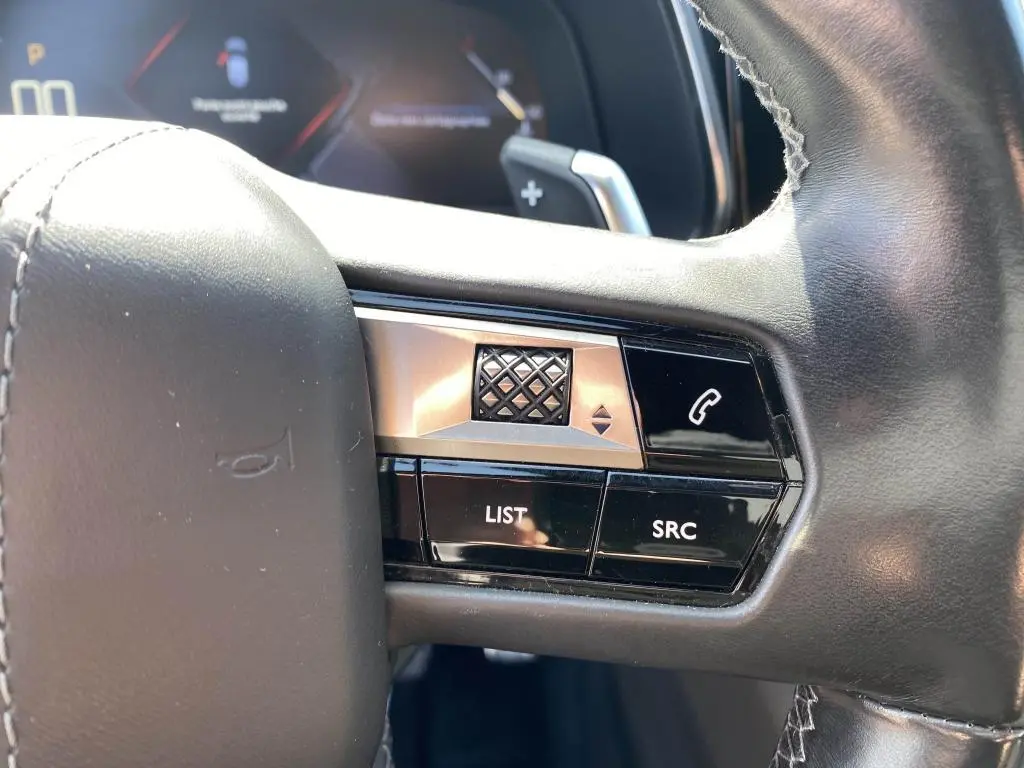 Gros plan sur les commandes gauche du volant noir du DS7 Crossback jaune clair, avec boutons LIST, SRC et téléphone.