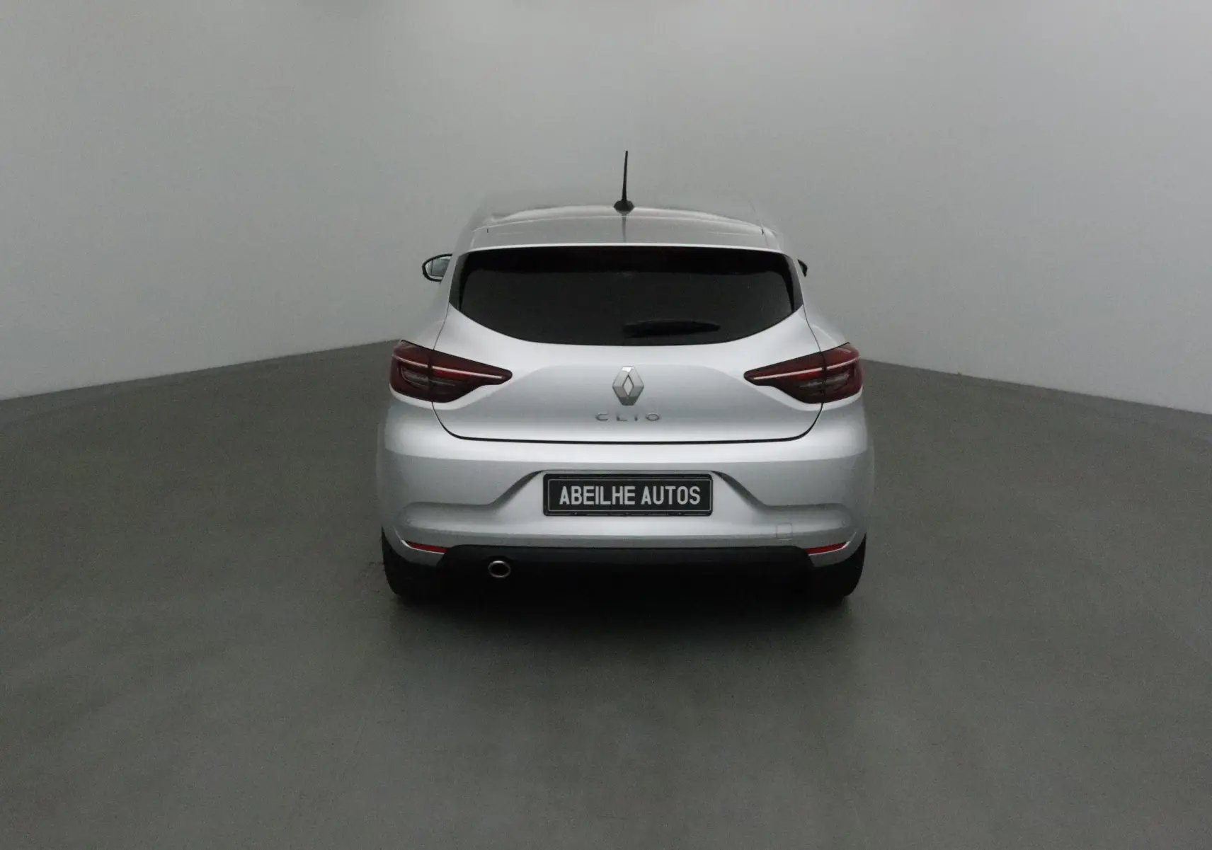 Vue arrière d'une Renault Clio V gris platine avec feux arrière LED et plaque Abeilhe Autos visible.