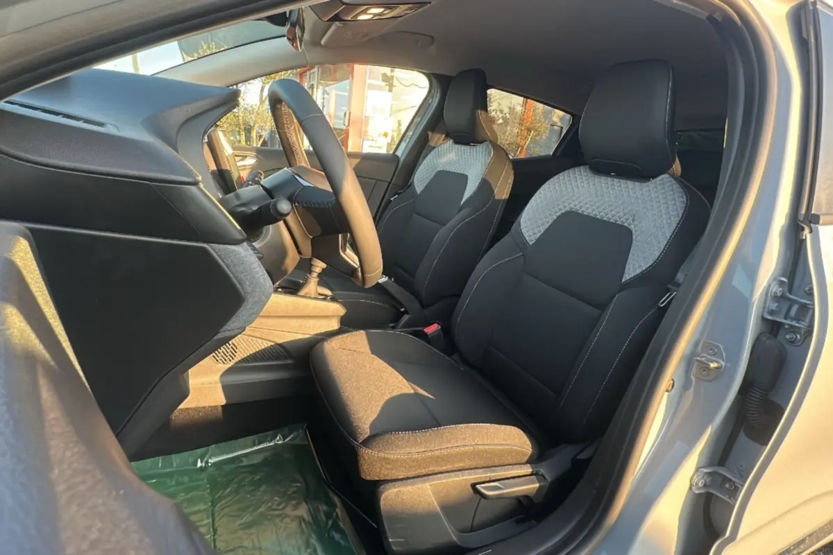Intérieur avant droit de la Renault Clio 2025 gris rafale, sièges tissu bicolore avec motifs géométriques.