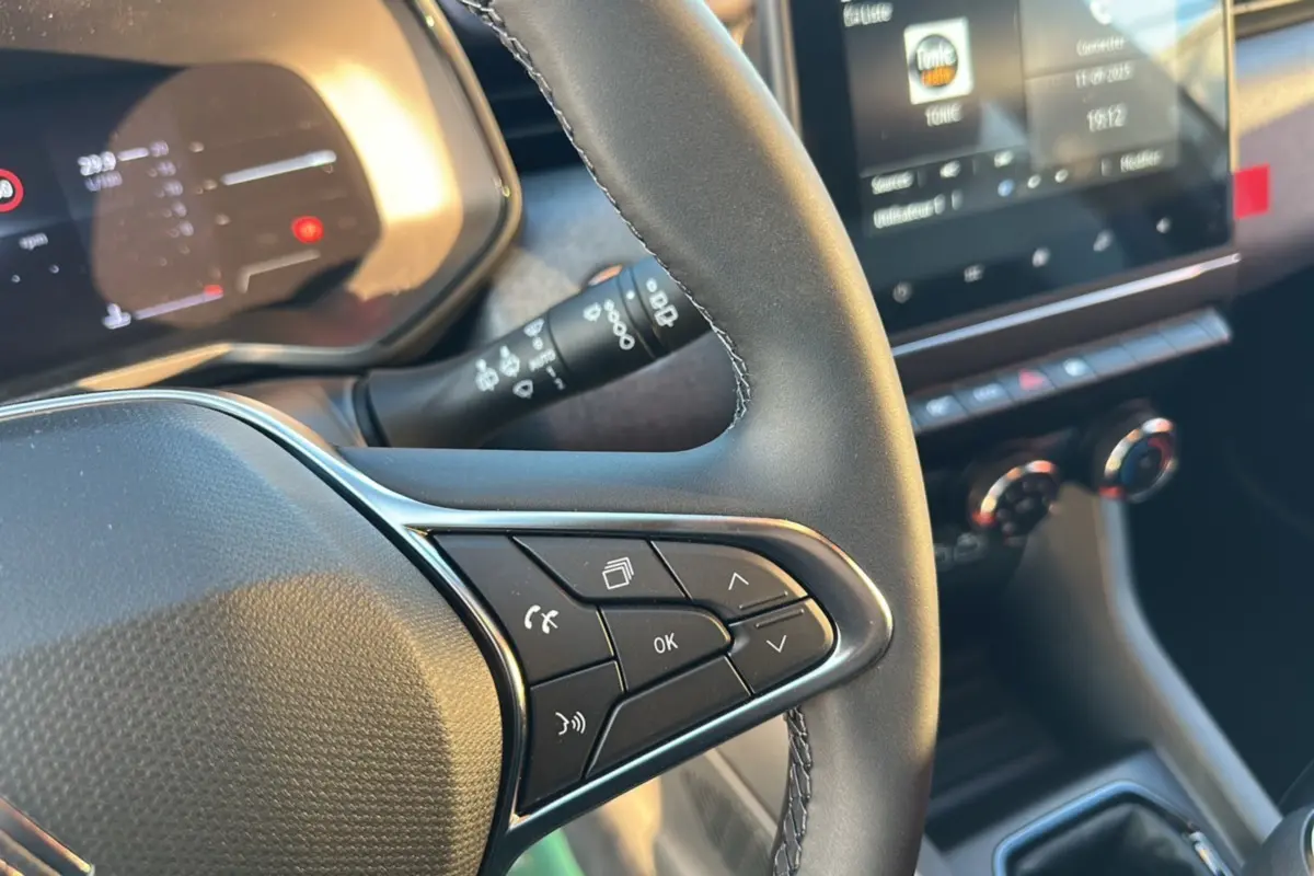 Gros plan sur le volant de la Renault Clio DCI 100 Evolution Camera 2025 avec commandes intégrées et tableau de bord numérique.