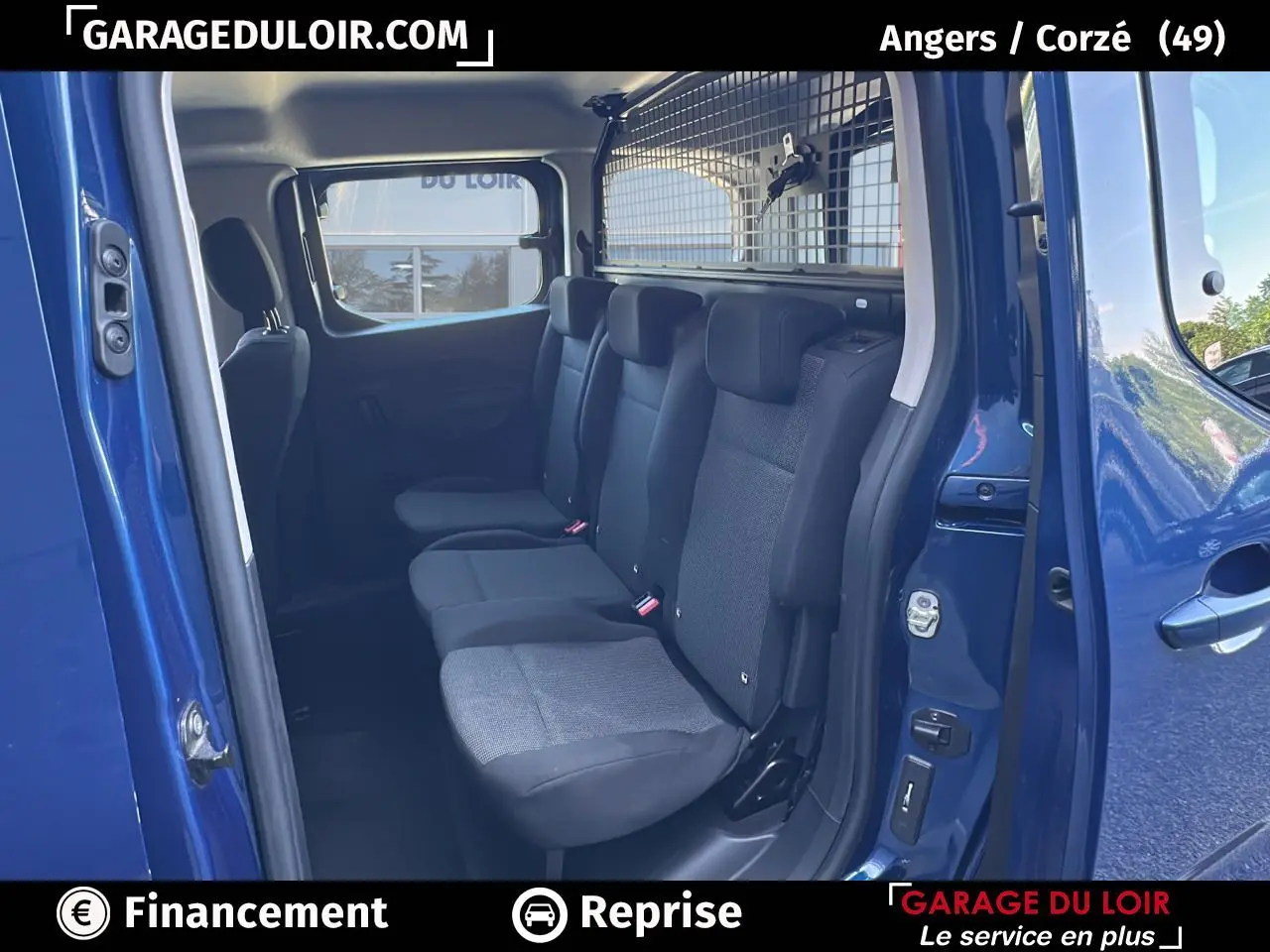 Vue intérieure côté droit sur la banquette arrière noire du Peugeot Rifter bleu avec cloison métallique de séparation