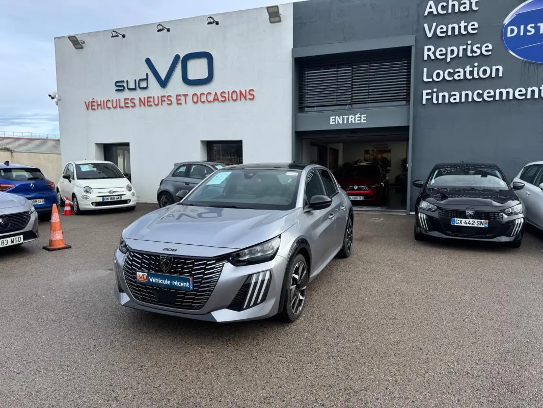 Peugeot 208 Hybrid gris vue 3/4 avant avec jantes alliage 17 pouces, stationnée devant un garage Sud VO.