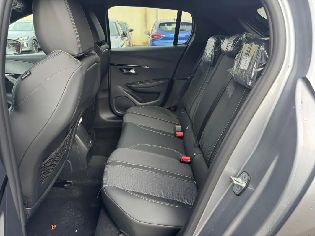Vue latérale droite de l'intérieur arrière gris du Peugeot 208 Hybrid 110 e-DCS6 GT avec sièges en tissu et cuir.