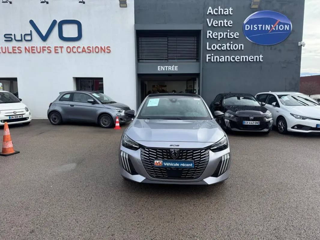 Peugeot 208 Hybrid gris vue de face, avec calandre noire distinctive et feux diurnes verticaux allumés.
