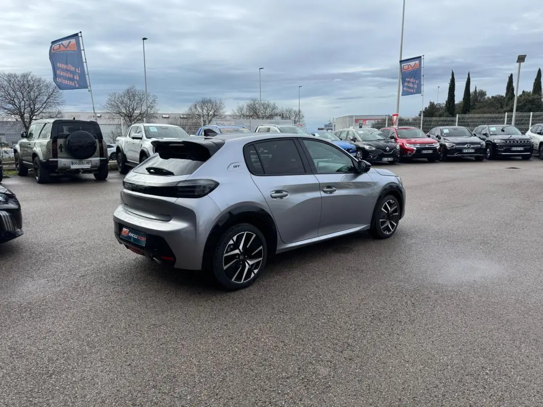 PEUGEOT 208 Hybrid 110 e-DCS6 GT gris vu en 3/4 arrière droit, avec jantes alliage 17 pouces et feux arrière noirs.