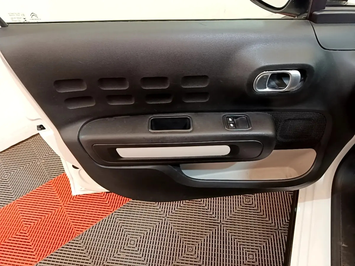 Vue rapprochée de la porte avant gauche blanche d'une Citroën C3 2022 avec panneau intérieur noir et poignée chromée.
