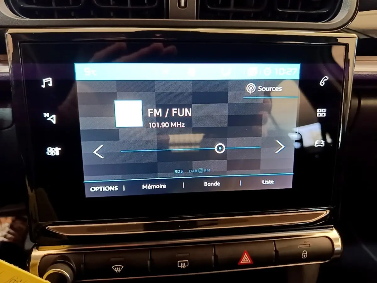 Écran tactile central de la Citroën C3 2022 affichant la radio FM avec commandes tactiles et boutons de climatisation en dessous.