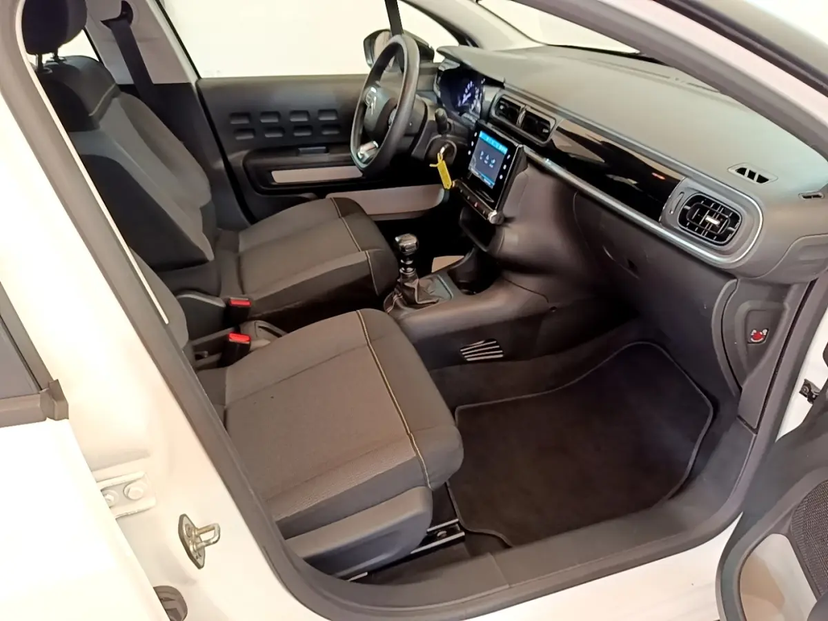 Intérieur côté conducteur d'une Citroën C3 blanche 2022, montrant sièges noirs et tableau de bord avec écran tactile.