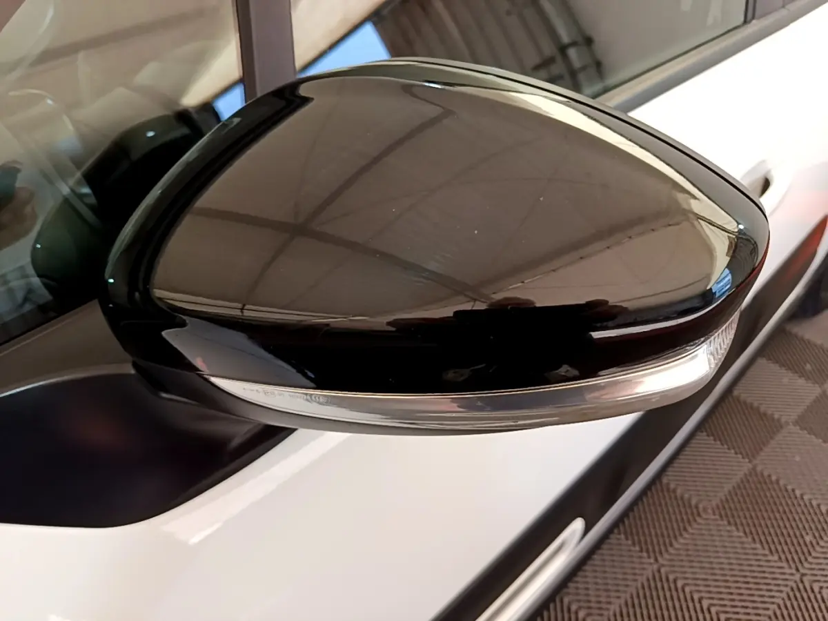 Gros plan sur le rétroviseur droit noir brillant avec clignotant intégré d'une Citroën C3 blanche vue de côté.