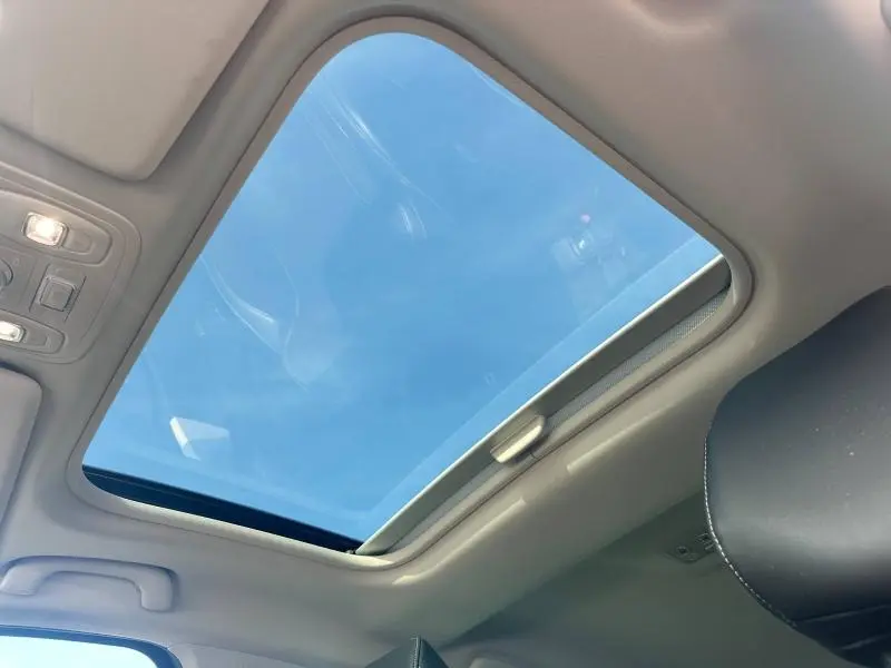 Toit ouvrant panoramique vu de l'intérieur sur Renault Mégane Break gris titanium, ciel bleu visible à travers.