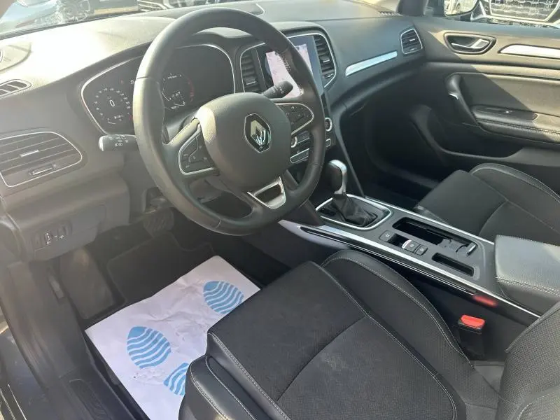 Vue intérieure côté conducteur de la Renault Mégane Break 2024, volant multifonction et sellerie noire en tissu et similicuir.