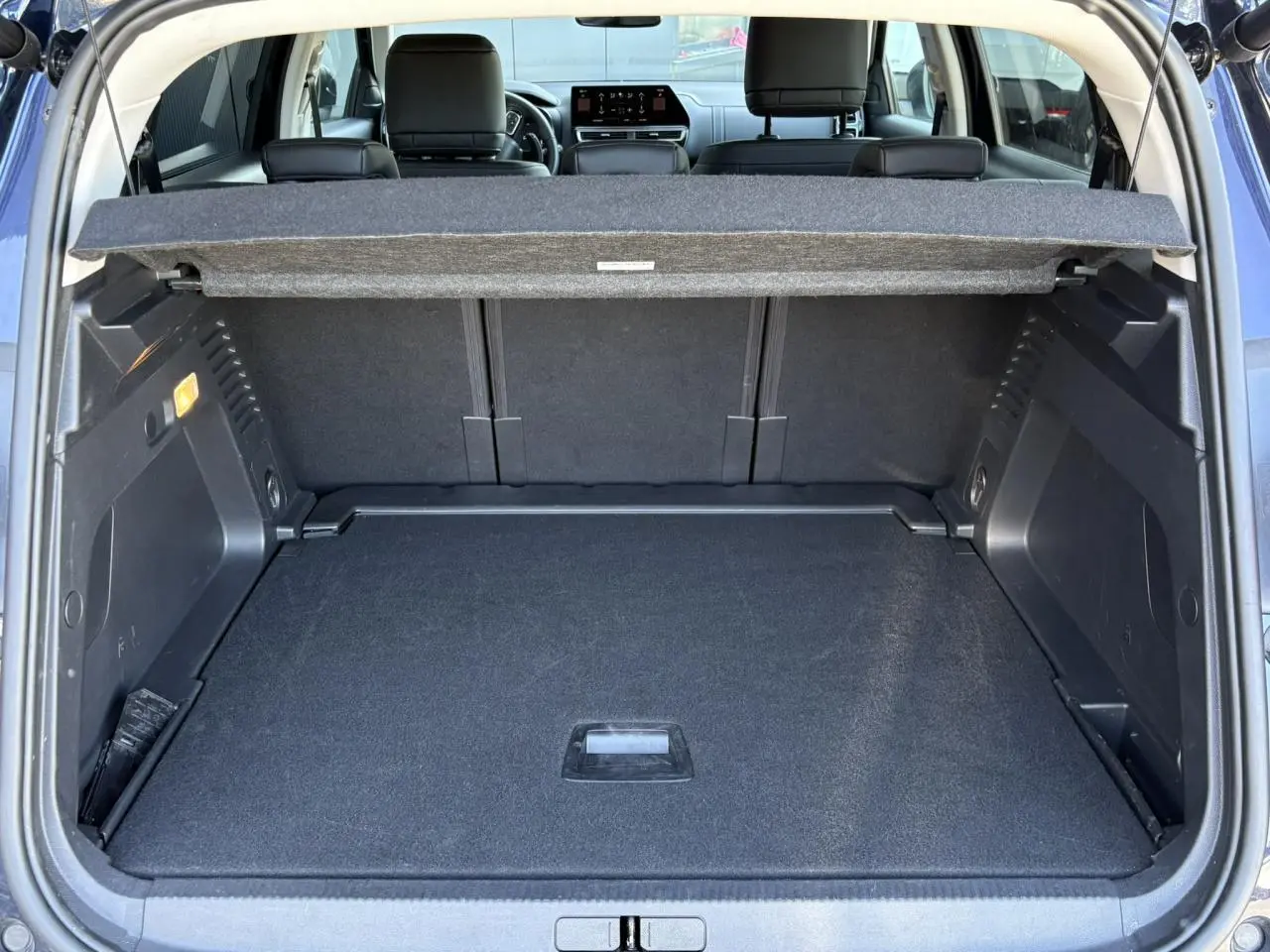 Vue arrière du coffre ouvert du Citroën C5 Aircross Hybrid 145 bleu Eclipse, montrant l'espace de chargement et la tablette cache-bagages.