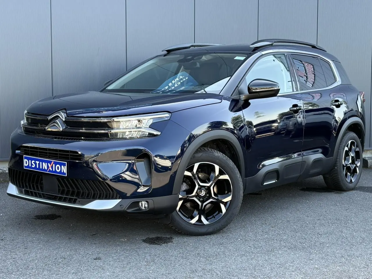 Vue 3/4 avant droite du Citroën C5 Aircross Hybrid bleu Eclipse avec jantes alliage bi-ton et barres de toit noires.
