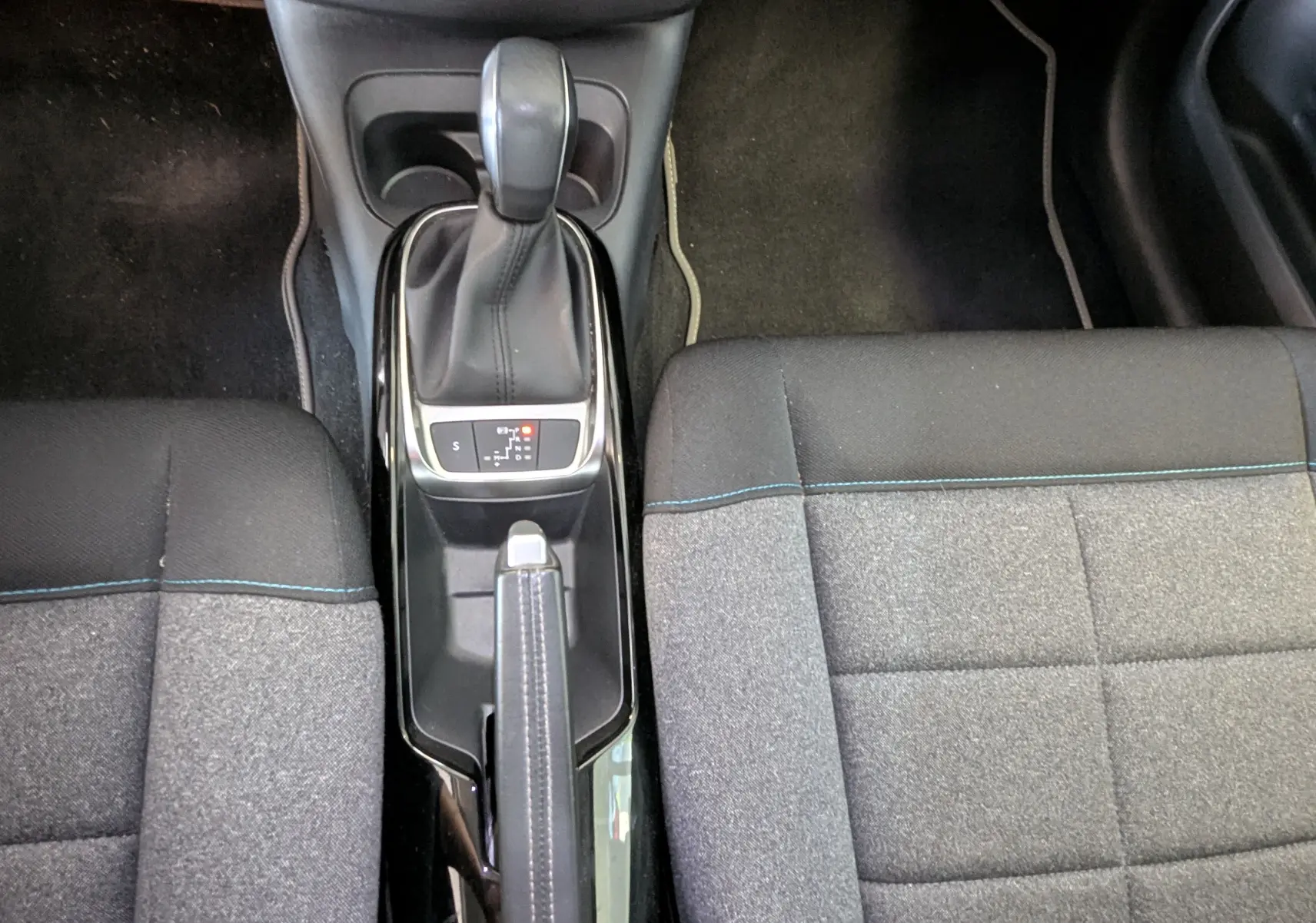 Vue plongeante sur la console centrale avec levier de boîte auto et sièges tissu gris du Citroën C4 Cactus blanc.