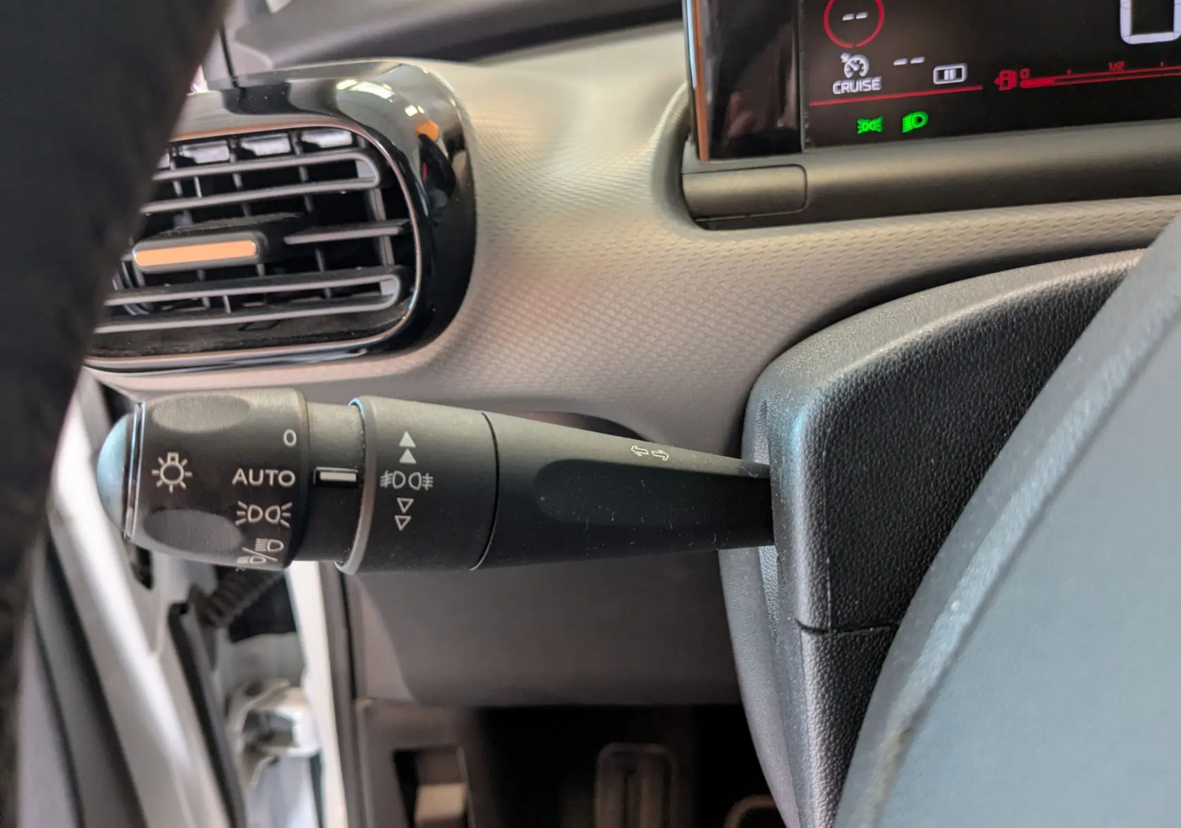 Gros plan sur la manette des feux et clignotants côté gauche du tableau de bord gris du Citroën C4 Cactus blanc 2019.
