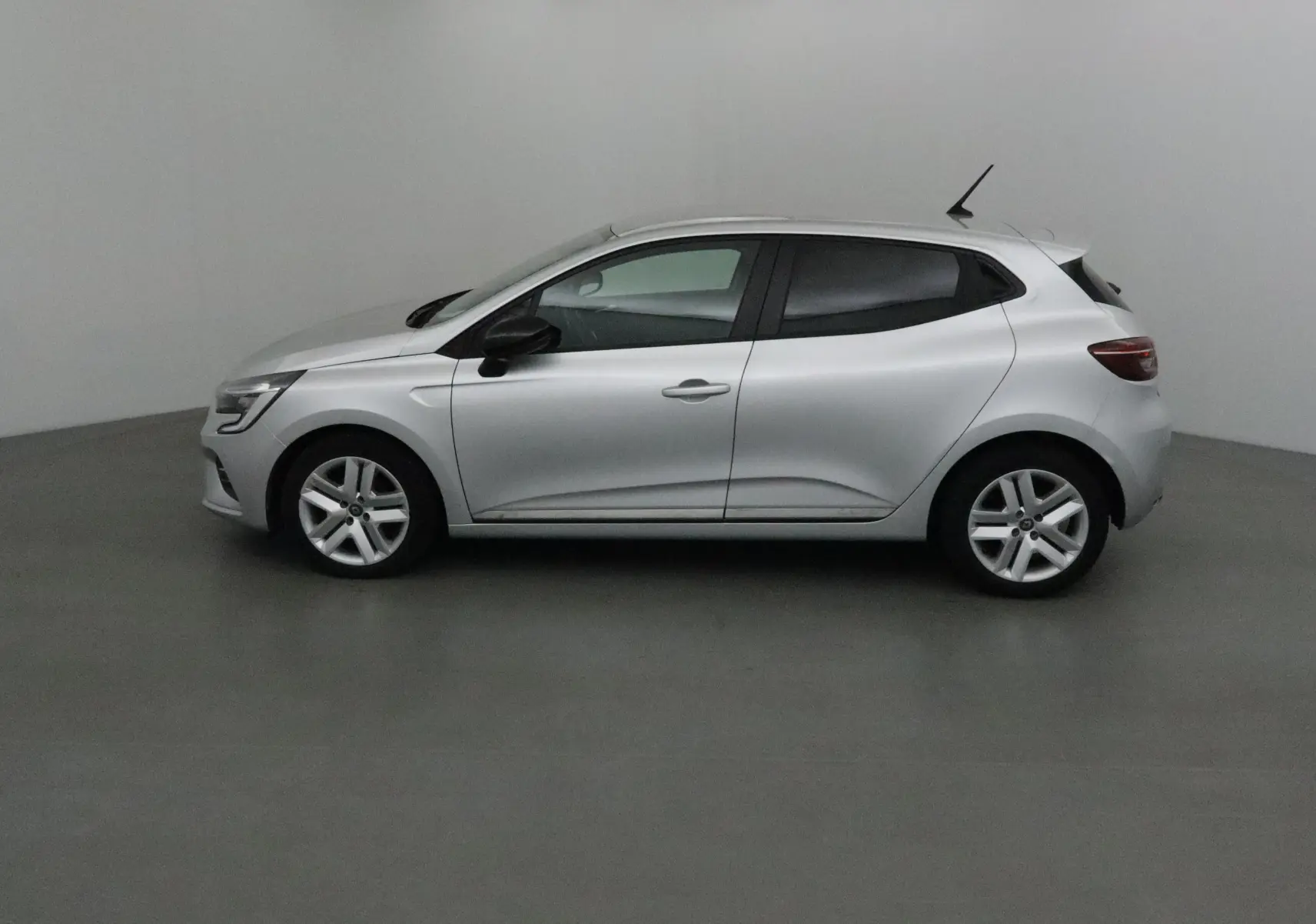 Profil côté gauche d'une Renault Clio V gris platine 2021, compacte et moderne dans un studio neutre.