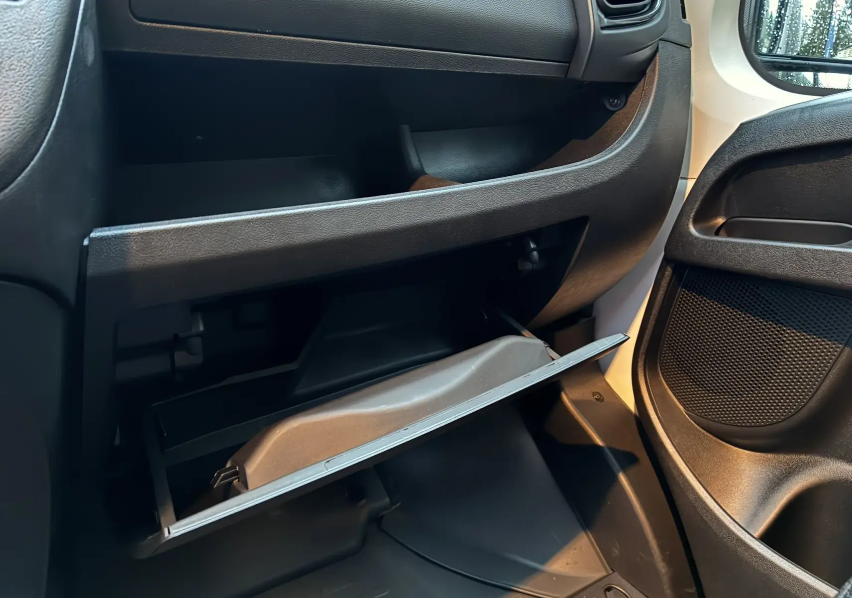 Vue intérieure côté passager du Fiat Ducato Fourgon 2025, boîte à gants ouverte avec tableau de bord noir et détails en tissu.