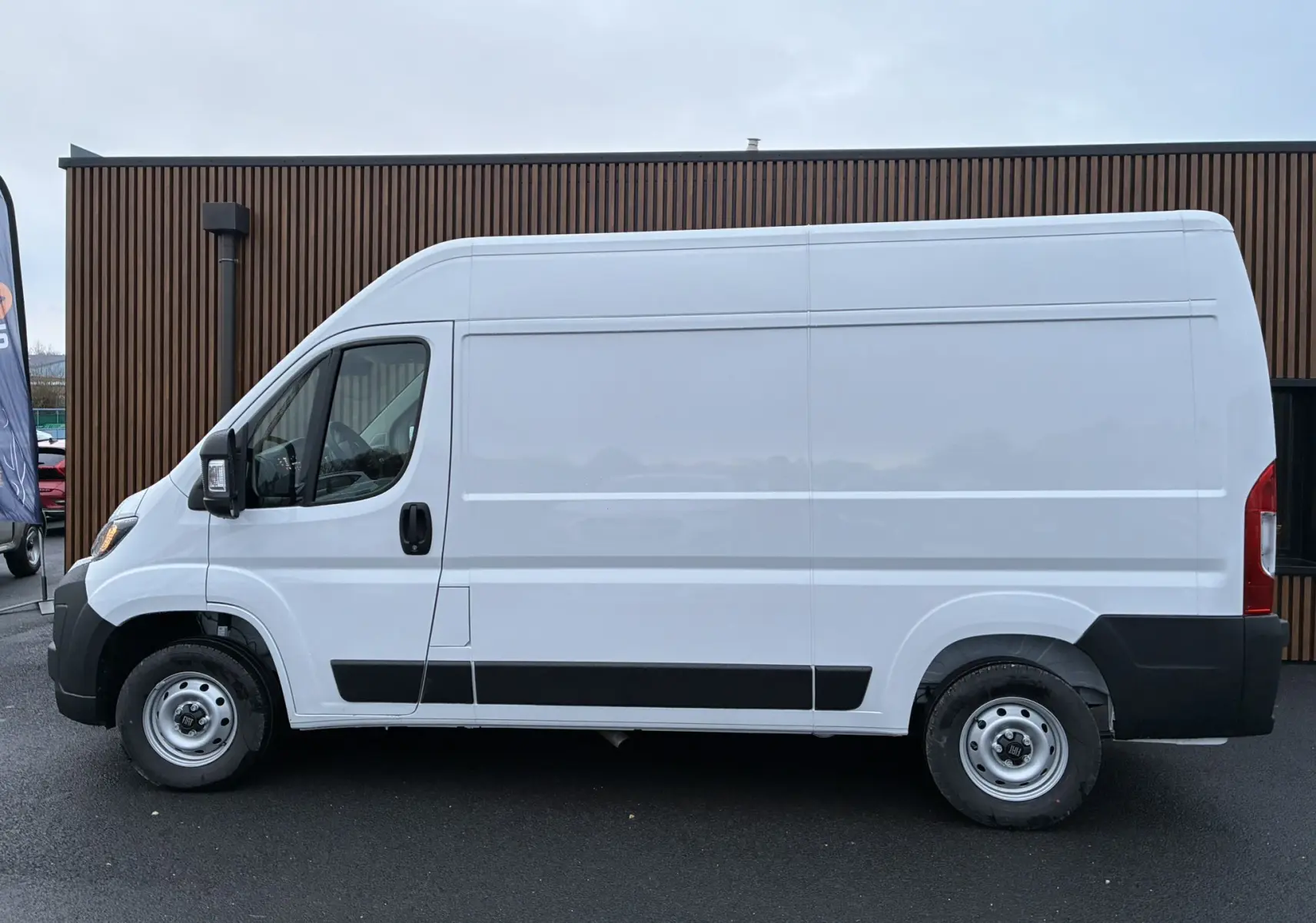 Vue latérale droite d’un FIAT Ducato Fourgon blanc 2025 avec protections noires sur bas de caisse et roues acier.