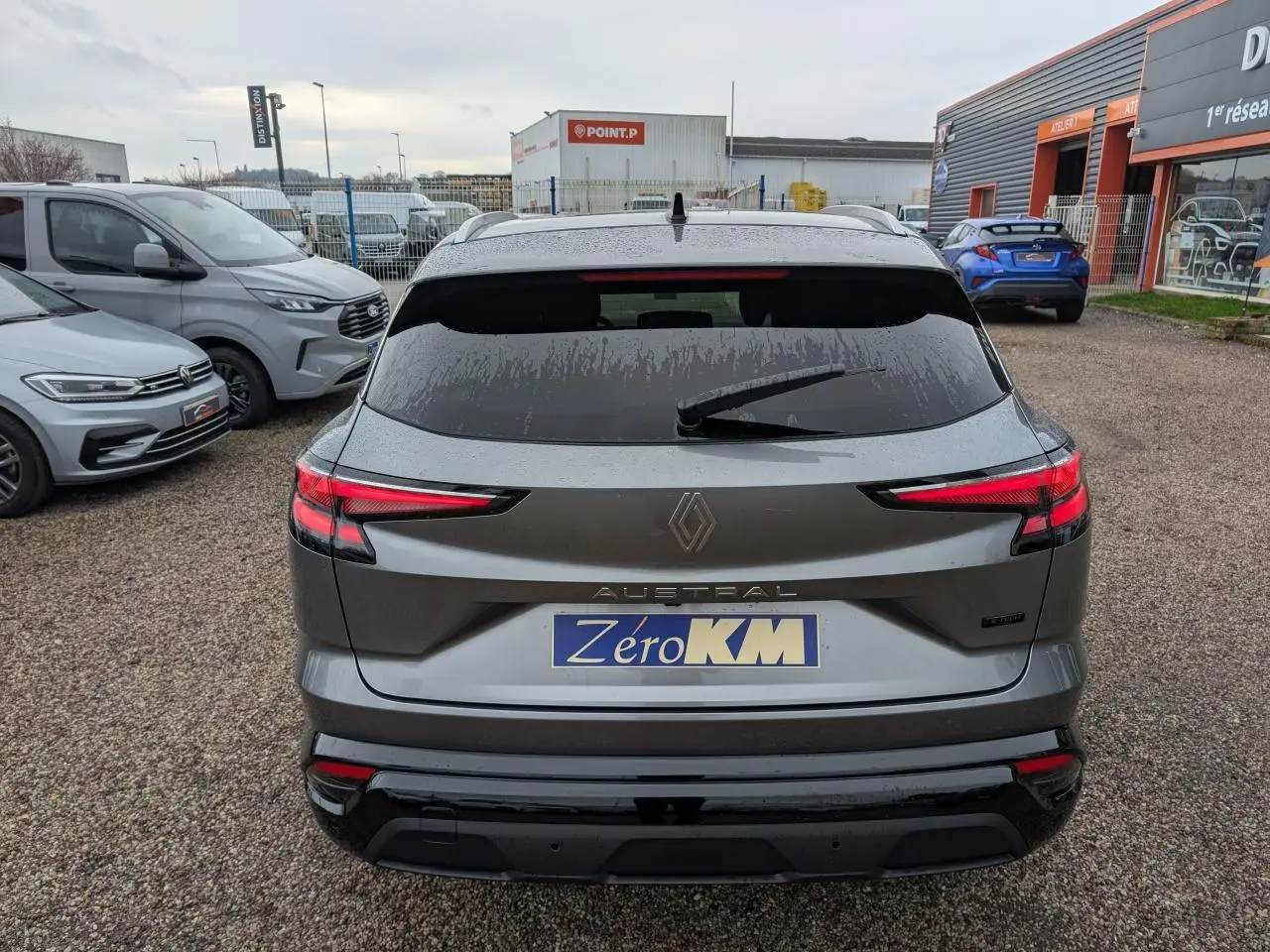 Vue arrière d'un Renault Austral gris avec feux LED étirés et hayon fermé sur un parking extérieur.