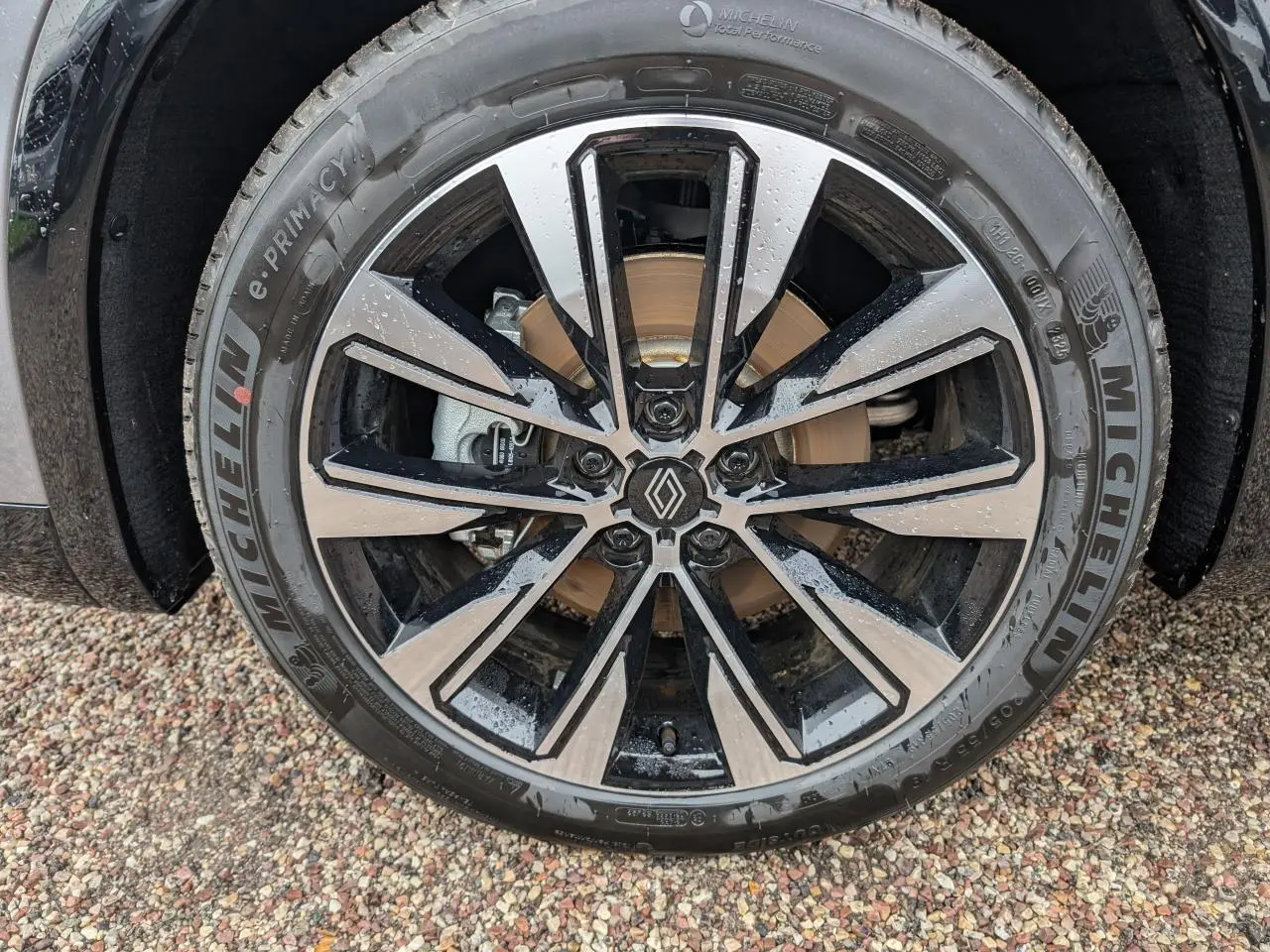 Gros plan sur la jante alliage diamantée noir brillant du Renault Austral gris, avec logo central visible.