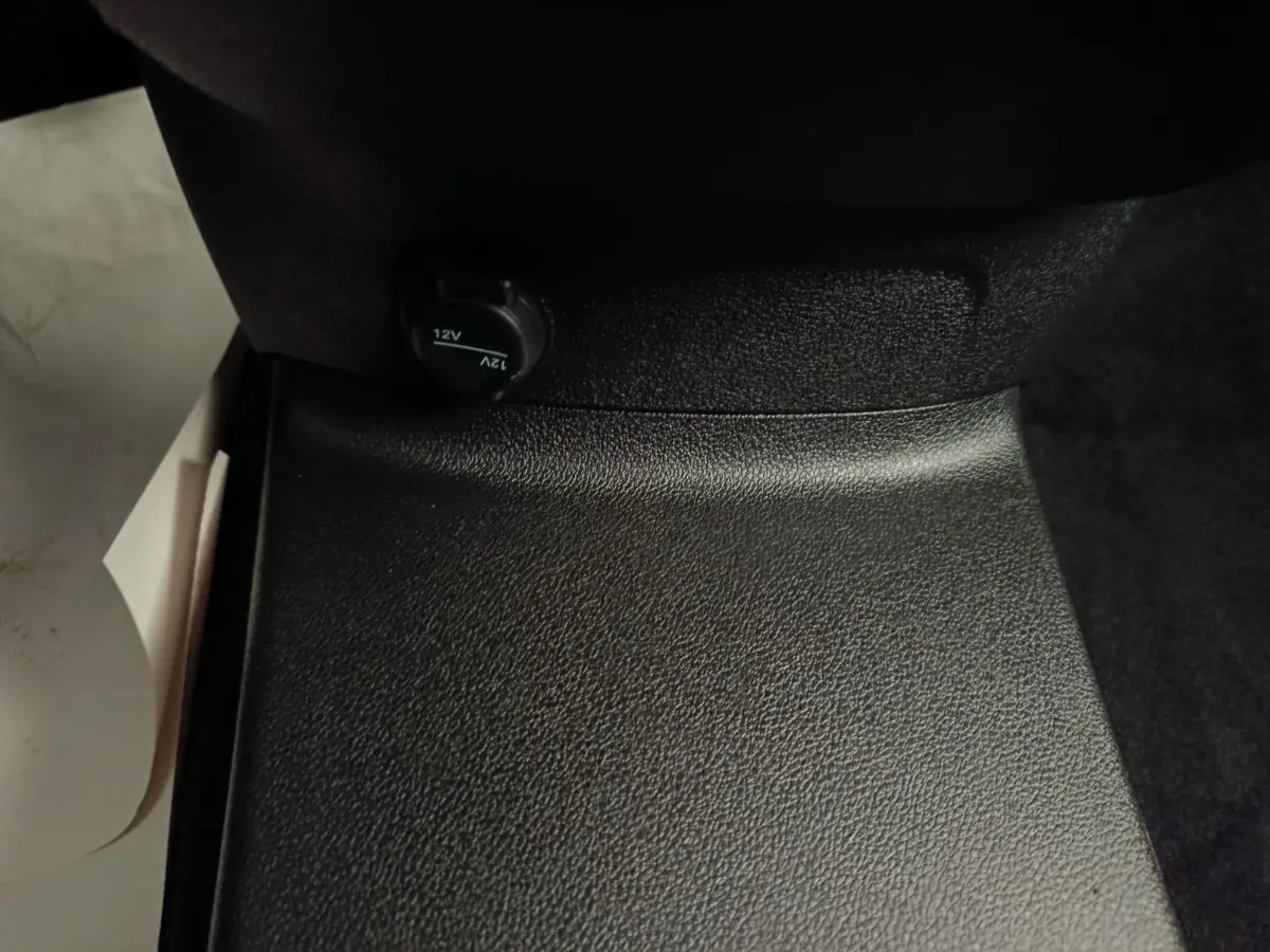 Prise 12V noire sous le siège passager du Peugeot Partner blanc, vue intérieure rapprochée du plancher.