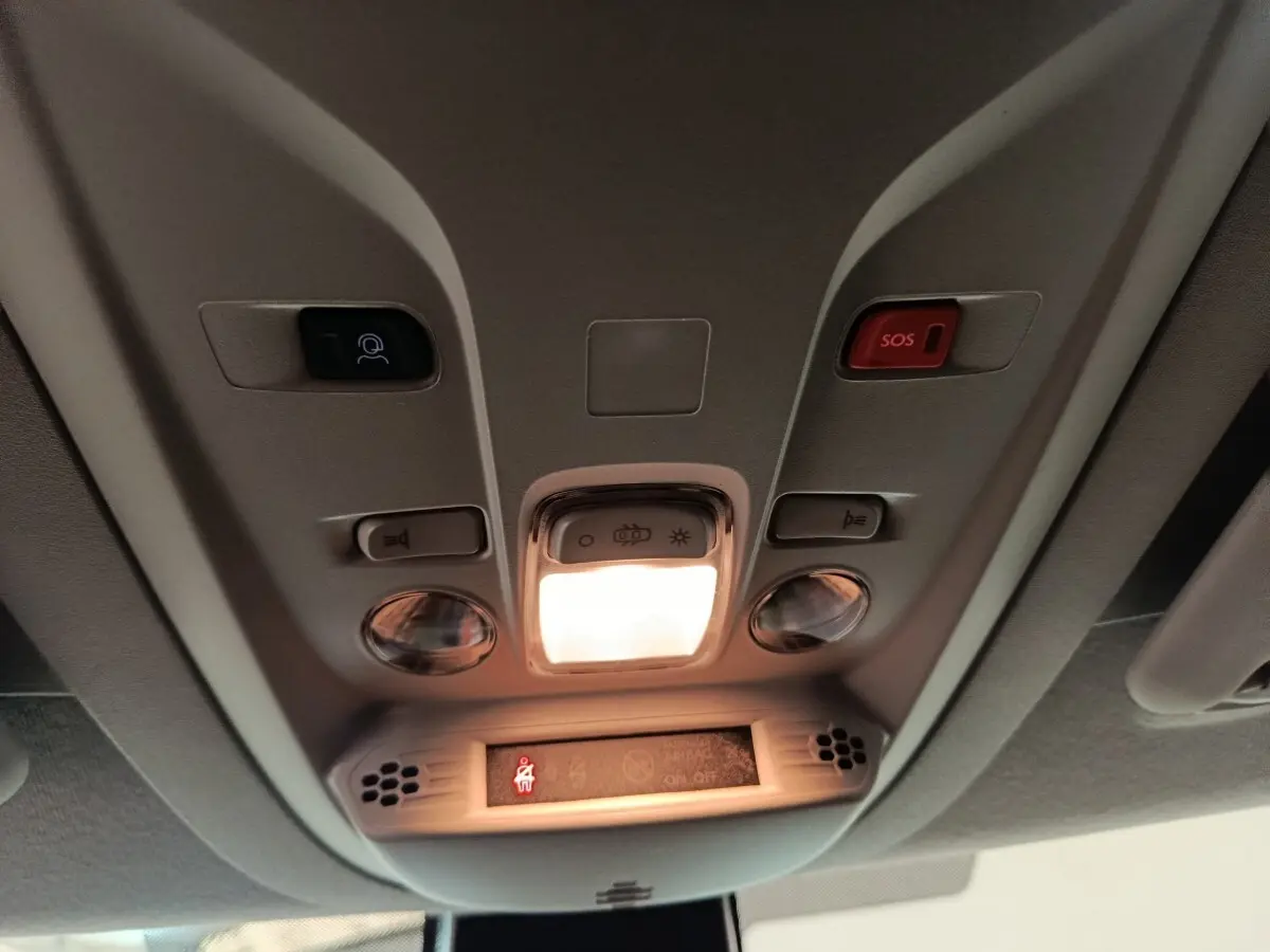 Vue intérieure du plafond avant du Peugeot Partner blanc 2025, avec éclairage central et bouton SOS rouge.