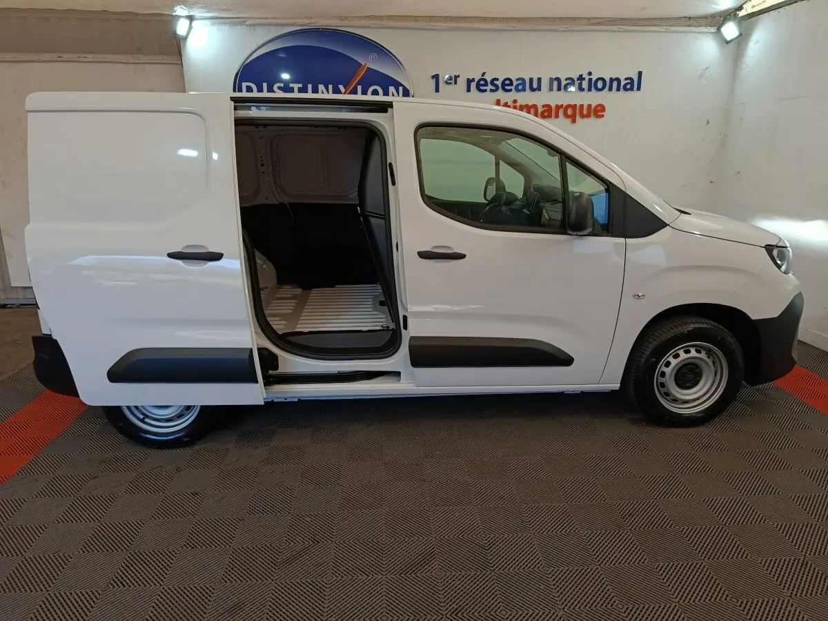 Vue latérale droite d’un Peugeot Partner blanc 2025 avec porte coulissante ouverte, montrant l’espace de chargement vide.