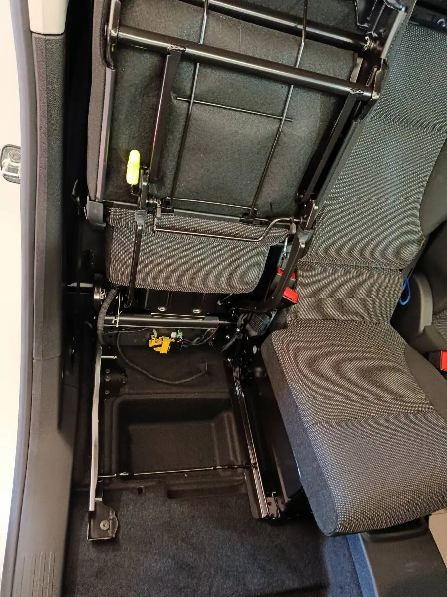 Vue intérieure rapprochée du siège passager relevé du Peugeot Partner blanc, montrant le rangement sous siège et la structure métallique.