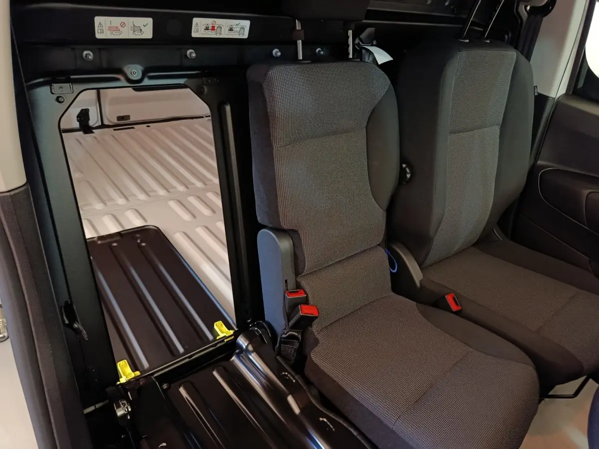 Vue intérieure sur les sièges avant gris et la cloison pleine séparant l'habitacle blanc du coffre du Peugeot Partner 2025.